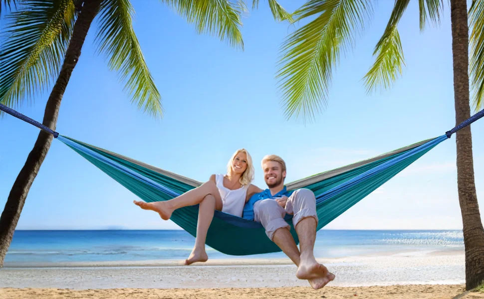 Couple relaxing in camping hammock on the beach